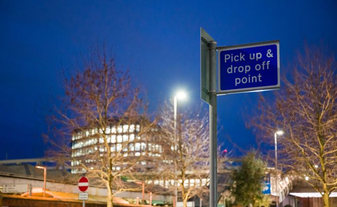 Pick up and drop off point sign against a dusk sky, indicating the accessible locations for Open Homes Nottingham's emergency accommodation services.