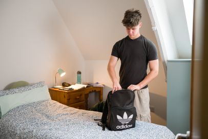 Young adult preparing his belongings in a serene and safe Open Homes Nottingham accommodation, highlighting the support for homeless youth in their journey towards stability.