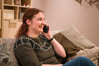A young couple from Open Homes Nottingham happily engaged with a smartphone, symbolising the connection and support offered to young homeless individuals.