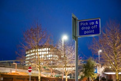 Pick up and drop off point sign against a dusk sky, indicating the accessible locations for Open Homes Nottingham's emergency accommodation services.