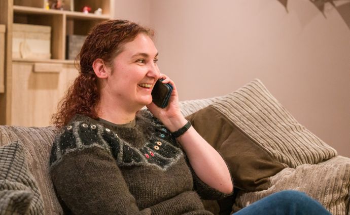 A young couple from Open Homes Nottingham happily engaged with a smartphone, symbolising the connection and support offered to young homeless individuals.